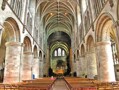 The nave of Hereford Cathedral showing the rounded arches of the Norman period above which are the pointed arches and elaborate rib vaulting of 14th century Gothic.